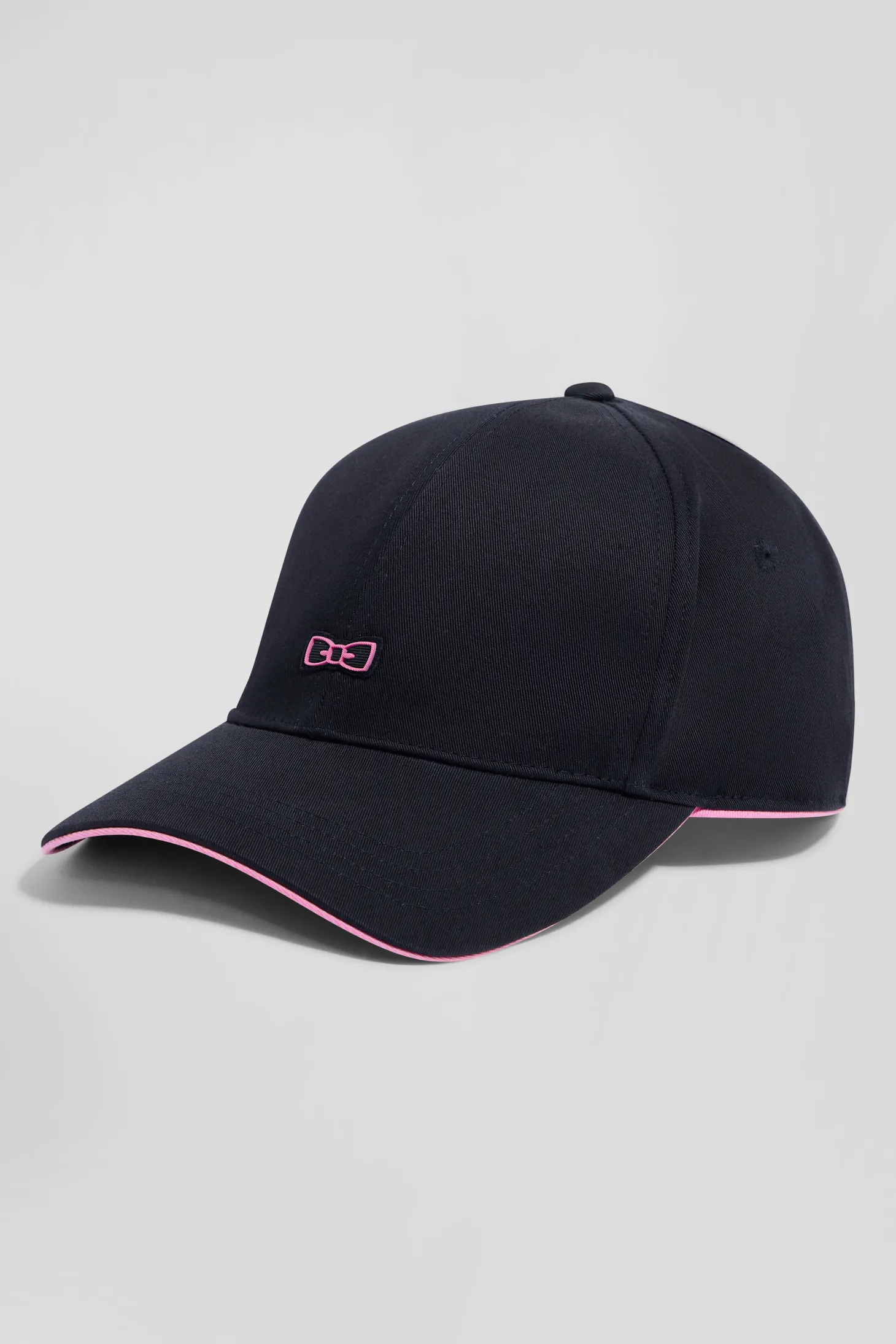 Navy blue cotton cap with bow tie badge and pink piping