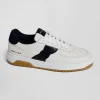 White low-top leather sneakers with navy blue cut-out